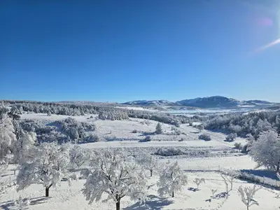 a snow covered field with trees and mountains at Apartman Stupe in Livno