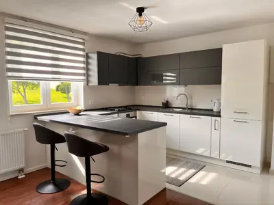 a kitchen with white cabinets and black counter tops at Apartman Stupe in Livno