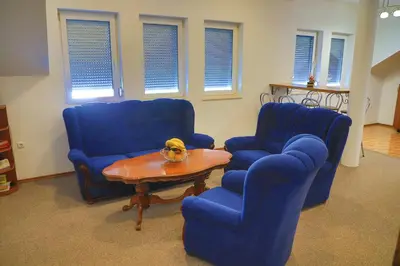 a living room with two blue chairs and a table at APARTMAN NAAJ in Bihać