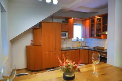 a kitchen with wooden cabinets and a table with wine glasses at APARTMAN NAAJ in Bihać