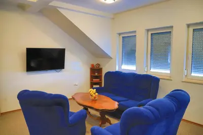 a living room with blue chairs and a tv at APARTMAN NAAJ in Bihać