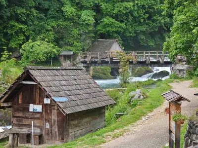 a small building next to a river with a bridge at Apartman Slapovi in Krupa na Vrbasu