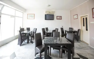 a dining room with tables and chairs and a tv at Pansion Kipovi in Tuzla