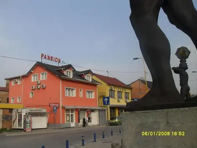 a city street with colorful buildings and a statue at Pansion Kipovi in Tuzla