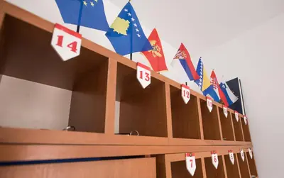 a row of wooden desks with flags on them at Pansion Kipovi in Tuzla