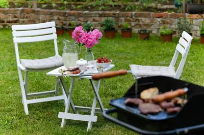 a table with two chairs and a grill with food and flowers at The Cosmic Gate 3 in Biskupići