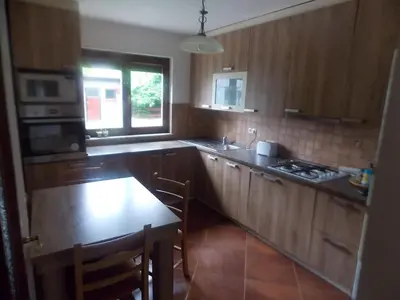 a kitchen with wooden cabinets and a table and a window at Kuća za odmor V&E in Bihać