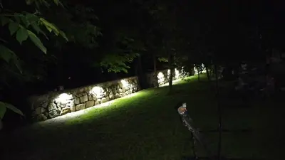 a garden lit up at night with a stone wall at Kuća za odmor V&E in Bihać