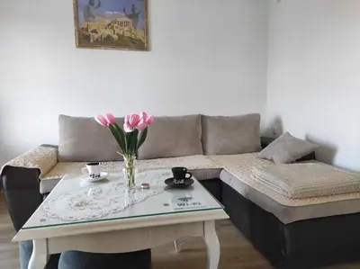 a living room with a couch and a table with pink flowers at Vikendica Ninic in Laktaši