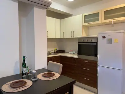 a kitchen with a table and a white refrigerator at Apartman AndjelA in Banja Luka