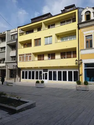 a yellow building with a courtyard in front of it at Penthouse in Jajce