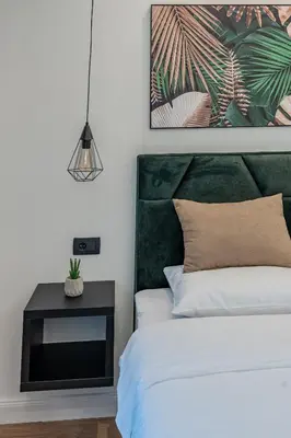 a bedroom with a bed with a green headboard and a table at Villa 4A Visoko in Visoko