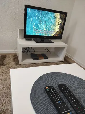 a television and two remote controls on a white stand at Apartment Kraljevac in Visoko