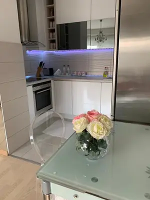 a vase of flowers on a glass table in a kitchen at Apartment Sweet Home Banja Luka in Banja Luka