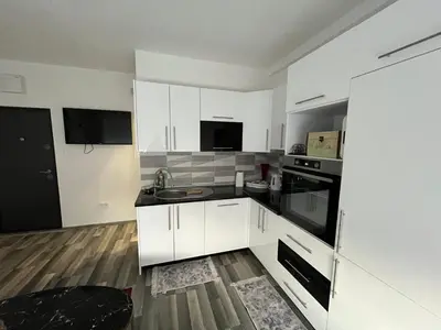 a kitchen with white cabinets and black appliances at Stan na dan, Pazar Tuzla - centar grada in Tuzla