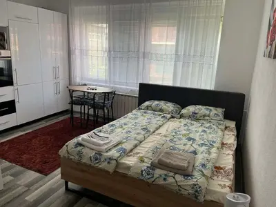 a bedroom with a bed with a table and a kitchen at Stan na dan, Pazar Tuzla - centar grada in Tuzla