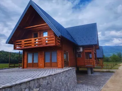 a wooden house with a blue roof on a stone wall at Bungalow Fly Fishing Kljuc River Sanica in Zolaći