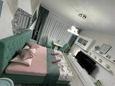 a bedroom with a bed with a green headboard at Apartman Kan in Bihać