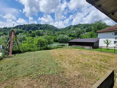 an open field with a barn and a lake at Apartman Sofija in Banja Luka