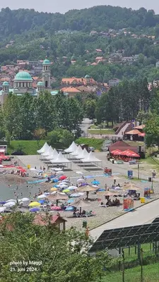a group of people on a beach with umbrellas at Apartman Deni in Tuzla