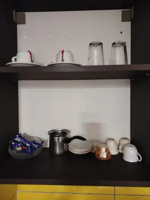 a kitchen shelf with dishes and pots and pans at Apartman Deni in Tuzla