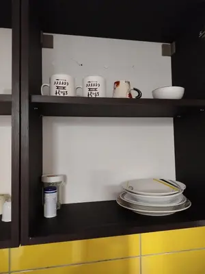a shelf with plates and dishes on it in a kitchen at Apartman Deni in Tuzla