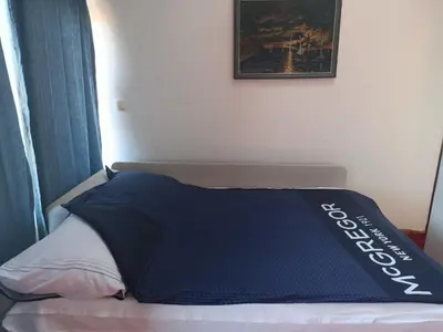 a bed with a blue blanket on top of it at Sunshine Apartments Visoko in Visoko
