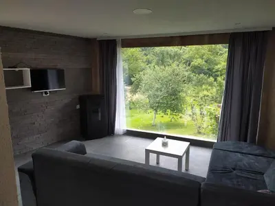 a living room with a couch and a large window at Lenilenii Bungalow in Jajce
