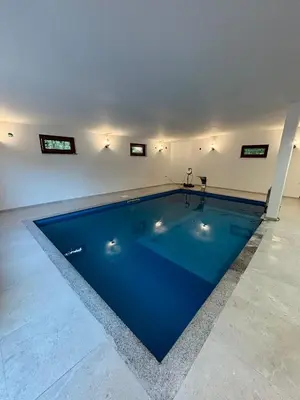 a large swimming pool in a white room with at Pool & Rest Holiday Home 3D in Bihać