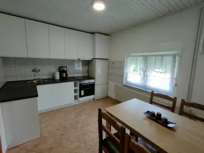 a kitchen with white cabinets and a wooden table with chairs at Riverside Panorama Apartment 2 near City Center Brko 2 in Banja Luka
