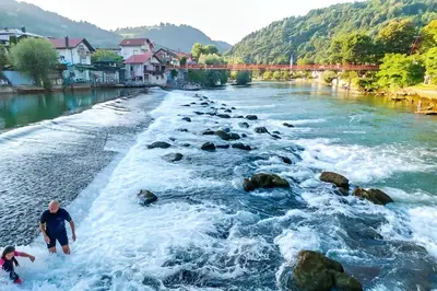 two people are standing in the rapids of a river at Riverside Panorama Apartment 2 near City Center Brko 2 in Banja Luka