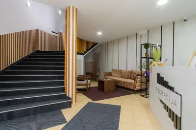 a lobby with a staircase with a couch and a chair at Stan lux Kašmir in Bugojno