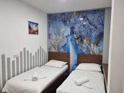 two beds in a room with a mural on the wall at Stan lux Kašmir in Bugojno