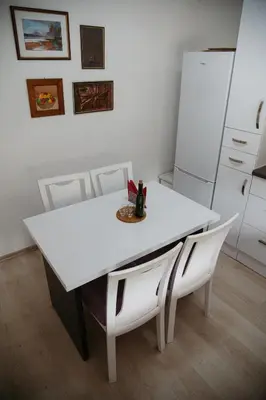 a white table with white chairs and a white refrigerator at Apartmani Romić R in Novi Travnik