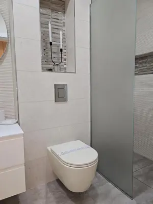 a bathroom with a toilet with two candles on the wall at ADAV Luxus Apartment in Visoko
