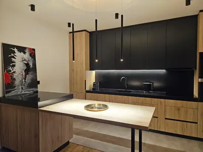 a kitchen with black cabinets and a wooden table at ADAV Luxus Apartment in Visoko