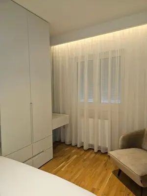 a bedroom with a white cabinet and a chair at ADAV Luxus Apartment in Visoko