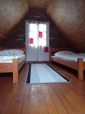 a attic room with two beds and a window at Vila Zlaja in Bihać