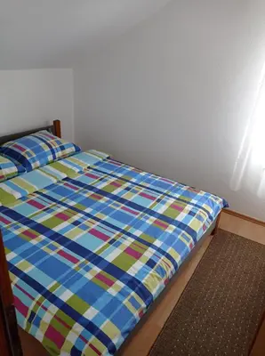 a bed with a blue comforter in a bedroom at Vila Zlaja in Bihać
