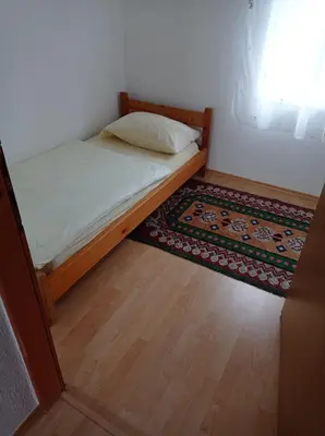 a small bedroom with a bed and a rug at Vila Zlaja in Bihać