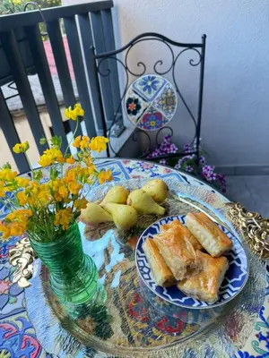 a table with a plate of food and a vase of flowers at Apartman My Choice in Bihać