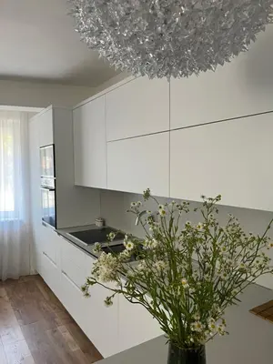 a kitchen with white cabinets and a vase with flowers at Apartman My Choice in Bihać