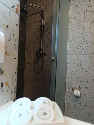 a bathroom with a shower and a sink with towels at Apartmani Leburic in Prnjavor