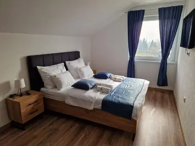 a bedroom with a bed with blue curtains and a window at Apartmani Leburic in Prnjavor