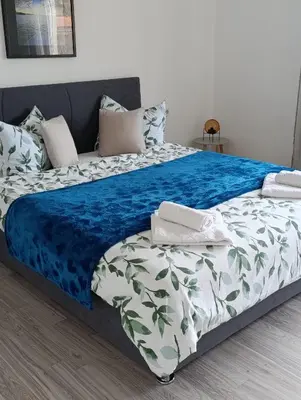 a bed with a blue and white blanket and pillows at Volijak 18 in Jajce