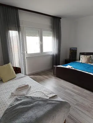 a bedroom with two beds and a large window at Volijak 18 in Jajce
