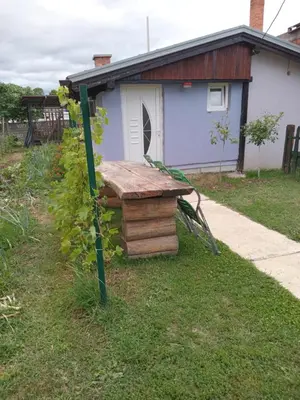 a wooden bench sitting in the grass in front of a house at Apartmani Primus in Bosanska Gradiška