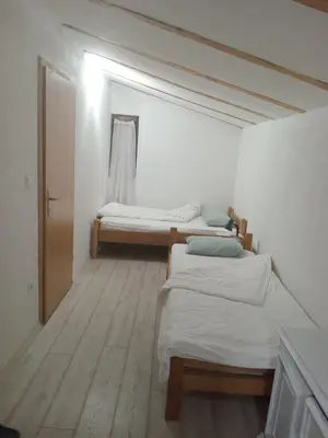 two beds in a room with white walls and wooden floors at Apartmani Primus in Bosanska Gradiška