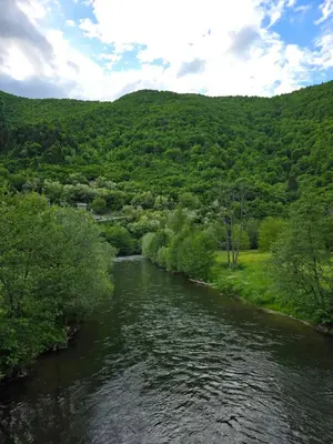 a river with green hills in the background at Apartment Riverstone Retreat in Jajce