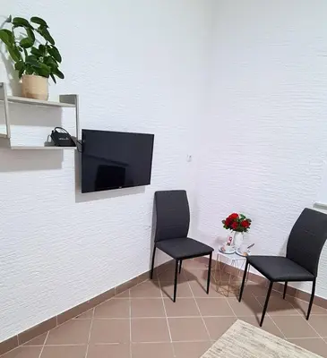 a room with two chairs and a tv on a wall at Prenoćište Dubravka in Livno